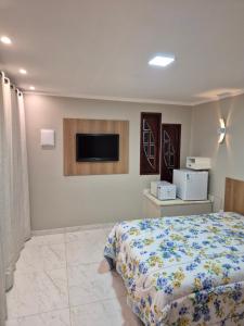 a bedroom with a bed and a tv on the wall at Suíte Praia Seca com ar condicionado in Araruama