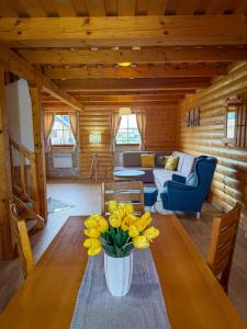 a living room with a table with yellow flowers on it at Tatralake Log Cabin - Drevenica pri Mare in Liptovský Mikuláš