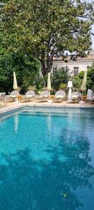 a large swimming pool with chairs and a group at Villa Aigarden in Avignon