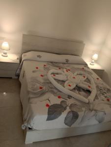 a white bed with leaves on it with two lamps at Thysia in Conversano