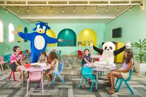 a group of children sitting at tables in a restaurant with a mascot at Houda Yasmine Marina & SPA in Hammamet