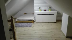 a attic room with a bed and a dresser at Apartament Monika Rewal z widokiem na morze in Rewal