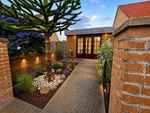 a garden with a tree and a brick house at Logement avec clim - thé, café et choco dispo in Oye-Plage