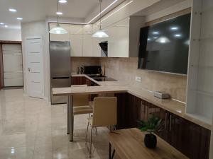 a kitchen with a table and a tv on the wall at Воскресенская 12 Евро in Dnipro +4 photos