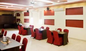 a dining room with red chairs and tables at Signature Suites Chennai in Chennai