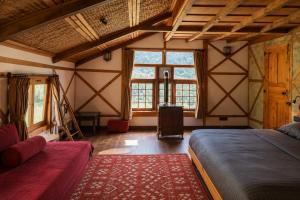 a bedroom with a bed and a couch and windows at Shepherd Barn Pahalgam in Pahalgām