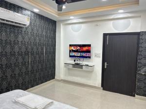 a bedroom with a tv on the wall and a door at Nawabz Hotel in Karnal