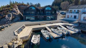a house with a dock with boats in the water at Eksklusiv Rorbu - Havblikk 1 - Båtutleie in Bekkjarvik
