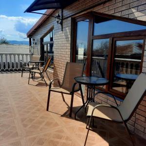 a patio with chairs and tables and windows at Guesthouse IMEDI in Velistsʼikhe