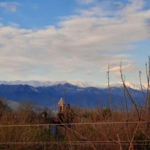 a church on a hill with mountains in the background at Guesthouse IMEDI in Velistsʼikhe