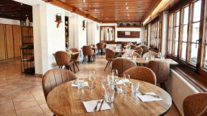 a restaurant with wooden tables and chairs and windows at L'Echo des Montagnes Armoy in Armoy