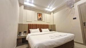 a bedroom with a large bed with white sheets at The City Hotel in Kānpur