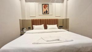 a large white bed with a robe on it at The City Hotel in Kānpur