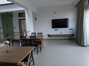 ein Wohnzimmer mit Tischen und einem Fernseher an der Wand in der Unterkunft Abhimaan in Mysore