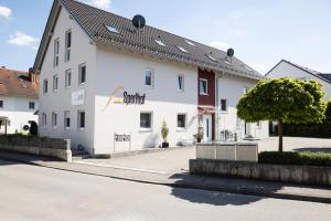 a white building with a tree in front of it at Pension Sperlhof in Erding