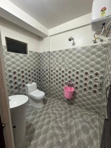 a bathroom with a toilet and a pink bucket at Cozy Inn in Cherrapunji
