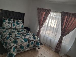 a bedroom with a bed and a window with curtains at Charles Guest House in Germiston +3 photos