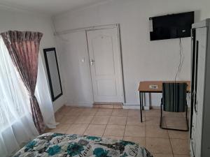 a bedroom with a bed and a table and a door at Charles Guest House in Germiston
