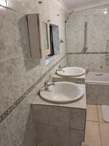 a bathroom with two sinks and a mirror at Charles Guest House in Germiston