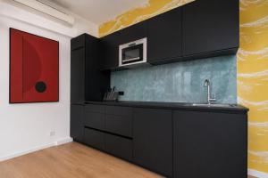 een keuken met zwarte kasten en een rood schilderij aan de muur bij The Suite Garden Hotel in Frankfurt am Main