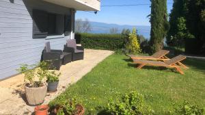 two benches sitting in the grass next to a house at Vue Lacustre in Publier