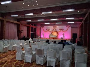 a large room with white chairs and a stage at The JANAKPURI in Ajmer