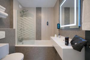 a bathroom with a shower and a toilet and a sink at Brit Hotel Le Cottage Le Mans Sud in Arnage