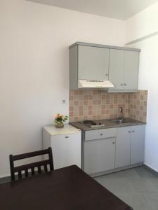 uma cozinha com armários brancos, um lavatório e uma mesa em Sofia Apartments SEA VIEW em Georgioupolis