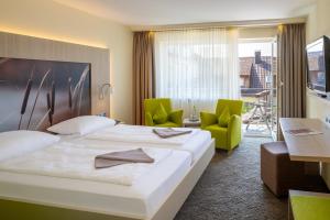 a hotel room with a large bed and green chairs at Hotel Gierer in Wasserburg +39 photos