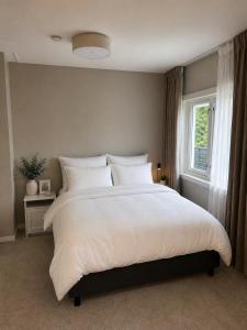 a bedroom with a large white bed with a window at Sunny Garden Stay in Sandvika