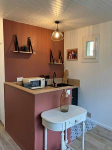 a kitchen with a counter with a microwave and a table at Studio Cosy près de la forêt in Saint-Prix