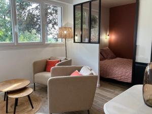 a living room with a couch and a chair and a bed at Studio Cosy près de la forêt in Saint-Prix