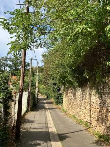 an empty road with trees and a stone wall at Studio Cosy près de la forêt in Saint-Prix