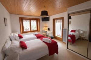 a bedroom with two beds with red and white sheets at L'Echo des Montagnes Armoy in Armoy