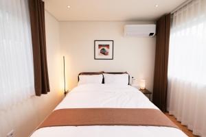 a bedroom with a large bed with white sheets at Stay SUM in Kwarye