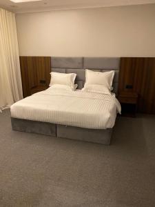 a bedroom with a bed with white sheets and pillows at شقق اضواء رفا للشقق المخدومة 4 in Al Kharj