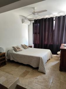 a bedroom with a bed and purple curtains at Cocon de Grand Anse in Petite Île
