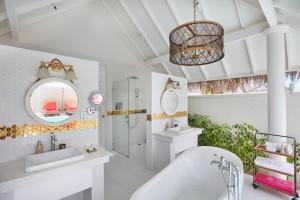 a bathroom with a tub and a sink and a mirror at Sun Siyam Iru Veli - 24 Hours Premium All Inclusive Dine Around with Free Sea Plane Transfers & Exclusive Inclusions in Dhaalu Atoll