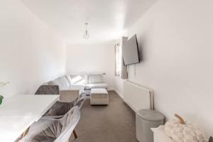 a white living room with a couch and a tv at Spacious Riverside View Bungalow in Oxford