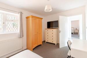 a bedroom with a television and a dresser with a cabinet at Spacious Riverside View Bungalow in Oxford