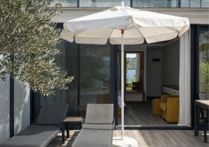 a white umbrella sitting on a patio with chairs at Kalkan Beach Park Hotel in Kaş