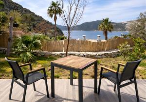 a table and two chairs on a patio with a view of the water at Kalkan Beach Park Hotel in Kaş