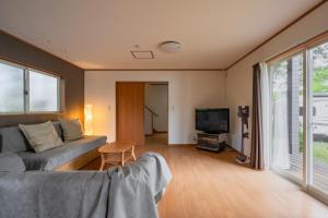 a living room with a couch and a tv at DogrunCafe & Resorts JENNIE West-Karuizawa in Miyota