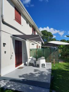 a white house with a patio with two umbrellas at Résidence Prune café in Le Moule +4 photos