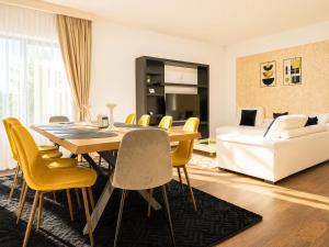 a dining room with a table and yellow chairs at Vila Panorama - Bunloc in Săcele
