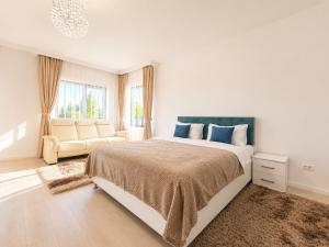 a white bedroom with a large bed and a couch at Vila Panorama - Bunloc in Săcele