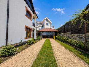 a house with a brick walkway next to a building at Vila Panorama - Bunloc in Săcele