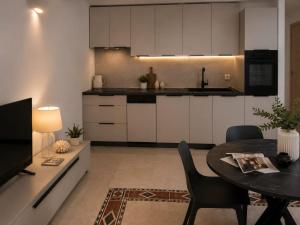 a kitchen with white cabinets and a table with chairs at App LOLLY in Selce +11 photos