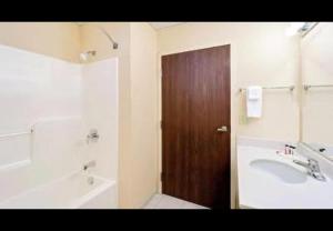a bathroom with a sink and a wooden door at Magnason Hotel in West Liberty +1 photo