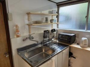 a kitchen with a sink and a microwave at Guest House Hana in Otsu